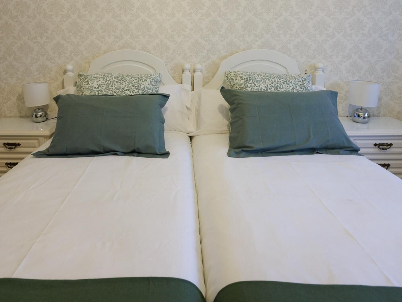 Un letto matrimoniale con due cuscini, un comodino con una lampada e una parete decorata.