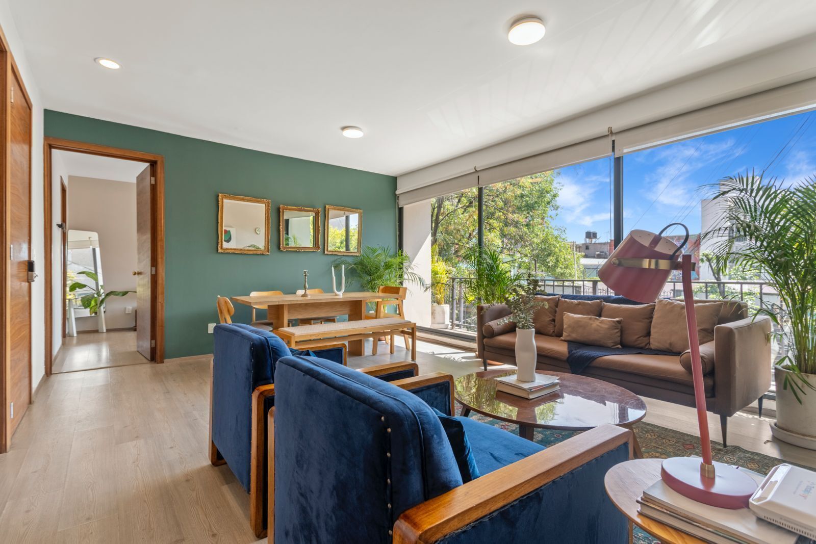 Un salon moderne avec un coin repas, de grandes fenêtres et un balcon agrémenté de plantes.