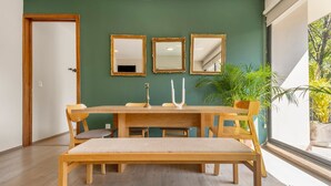 Un coin repas avec une table et des chaises en bois, un banc et trois miroirs accrochés au mur.