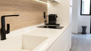 Una cocina moderna con encimera blanca, grifo negro y cafetera.