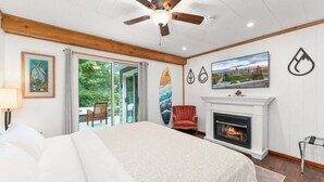 Une chambre à coucher avec un lit, une cheminée, un ventilateur de plafond et un téléviseur fixé au mur.