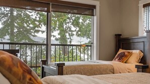 Ein Schlafzimmer mit großem Fenster, einem Bett mit gemustertem Überwurf und einem Nachttisch.