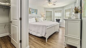A bedroom with a bed, a ceiling fan, and a dresser.