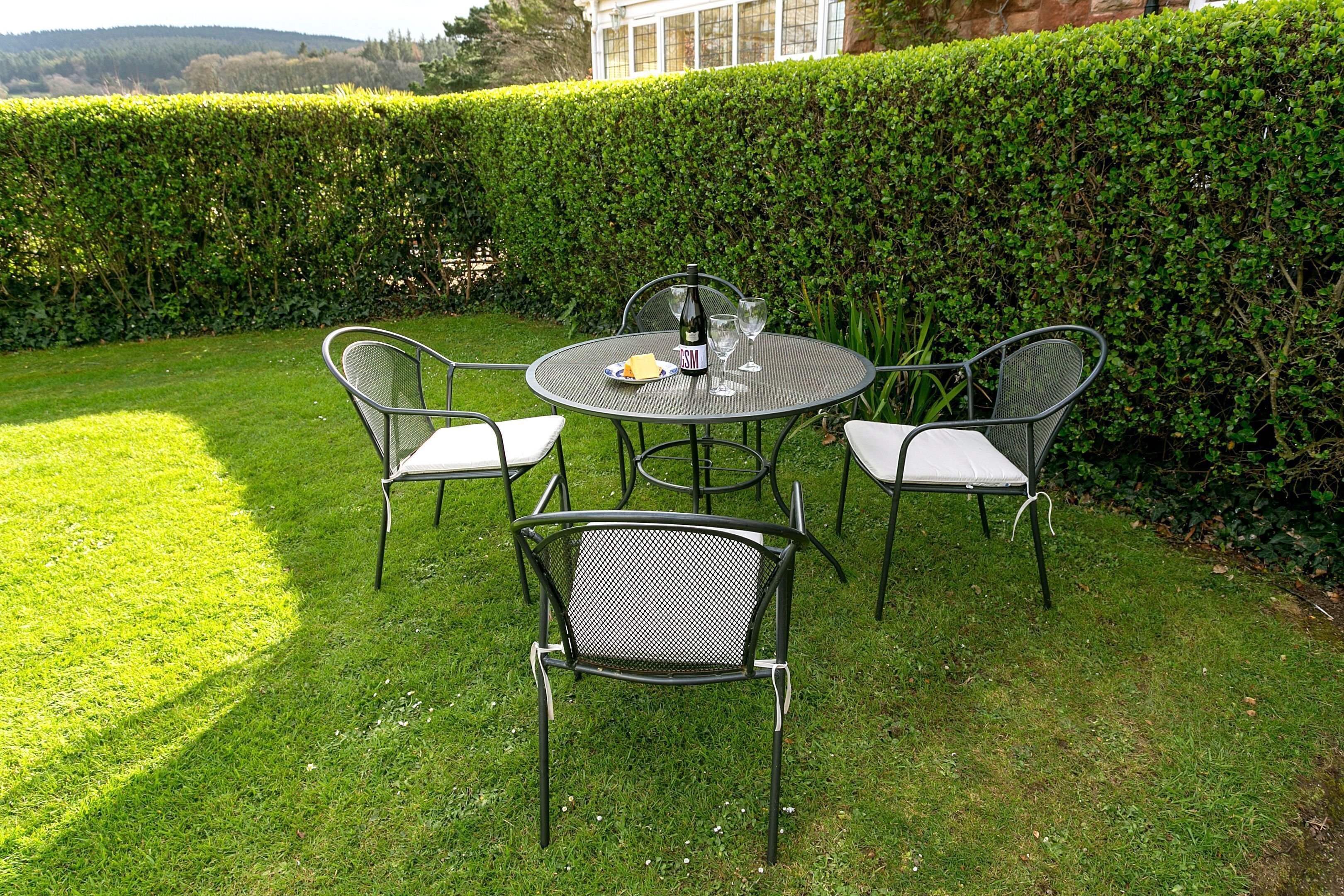 Une table ronde en métal, avec quatre chaises, une bouteille de vin et un verre dessus.