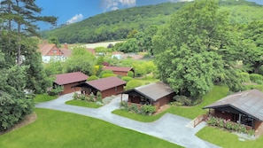 A rural property with multiple wooden cabins, a well-maintained lawn, and a view of a forested hillside.
