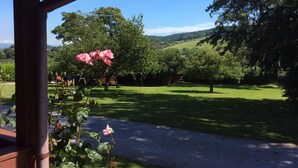 Un giardino con una pergola, un vialetto e vista su un paesaggio verde con alberi e colline.