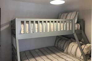 Un lit superposé avec une literie à rayures et une échelle.