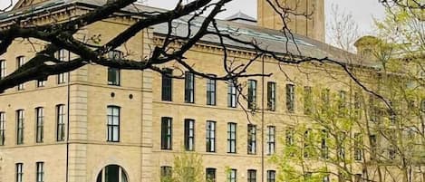 A large, multi-story building with a symmetrical facade, a central arched window, and a water feature in front.