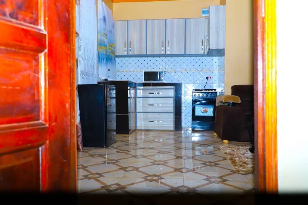Une cuisine avec des meubles blancs, un four à micro-ondes, un réfrigérateur et un four traditionnel.