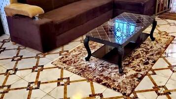 Un salon avec un canapé marron, une table basse en verre et des carreaux de sol à motifs.