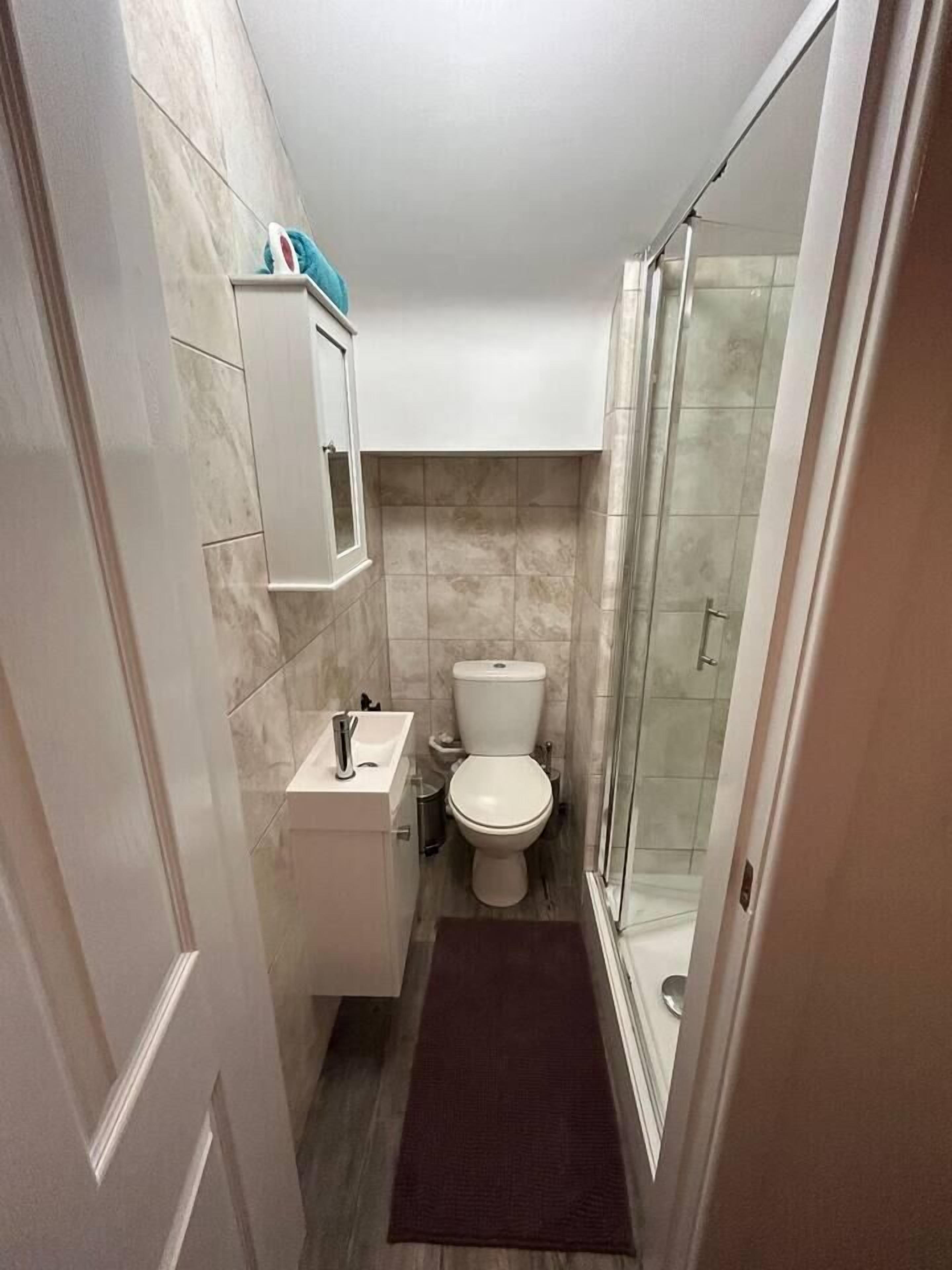 A compact bathroom with a toilet, sink, and a shower area.