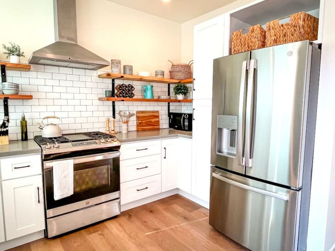 A modern kitchen with white cabinets, a stainless steel stove, and a large refrigerator.