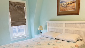 A bedroom with a bed, a window with a blind, a lamp, and a framed picture on the wall. - Cozy beach-inspired home! Close walk to boardwalk and beach! (Ocean City)