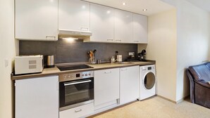 Eine moderne Küche mit integriertem Backofen, Mikrowelle und Waschmaschine, einer Kaffeemaschine und einem Toaster auf der Arbeitsfläche.