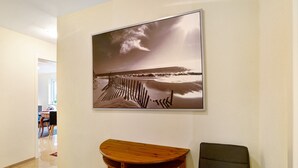 Ein Flur mit einem gerahmten Foto einer Strandansicht, einer hölzernen Bank und einem schwarzen Stuhl.