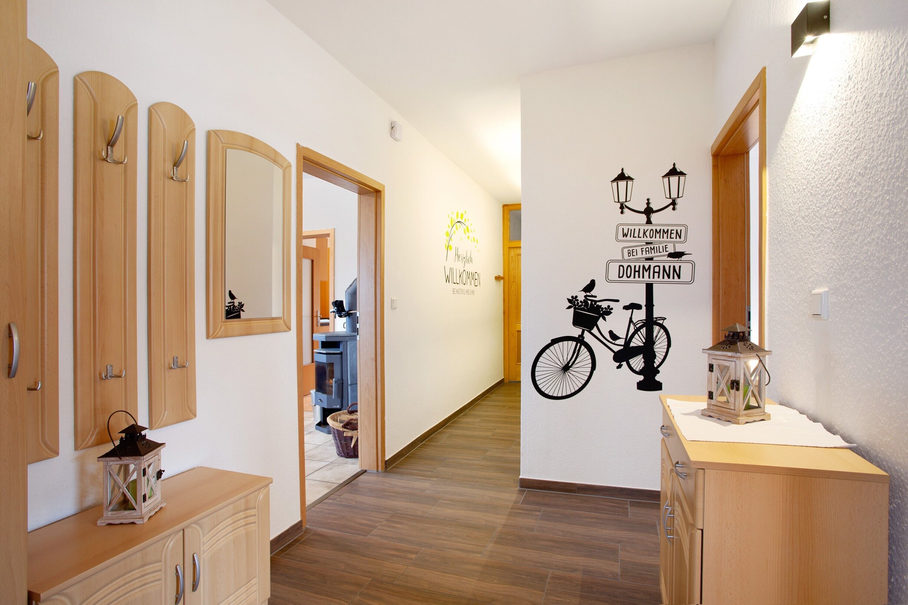 A hallway with wooden cabinets, a mirror, and a wall with a welcome sign and bicycle decoration.