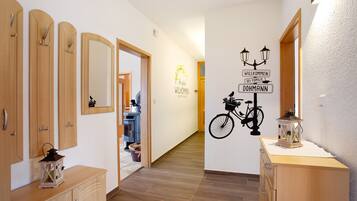 A hallway with wooden cabinets, a mirror, and a wall with a welcome sign and bicycle decoration.