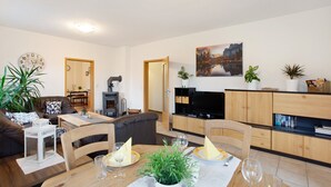 Ein Wohnzimmer mit einer Couch, einem Esstisch mit Stühlen, einem Fernseher und einem Kamin.