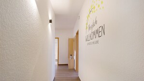 Ein Flur mit einem Schild, das 'Herzlich willkommen' und 'BEI MÖNSTER HIKES & BIKE' zeigt.