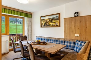Ein Essbereich mit Holztisch, Stühlen, einer Bank und einem Bild an der Wand.