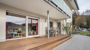 A modern house with a wooden deck, large sliding glass doors, and a dining area with outdoor furniture. - Apartment 'Fewo Zeit Zu Zweit' with Mountain View, Private Terrace and Wi-Fi (Sasbachwalden)