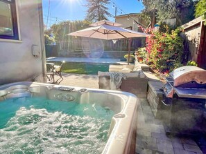 Uma banheira de hidromassagem com área de varanda, churrasqueira e piscina.
