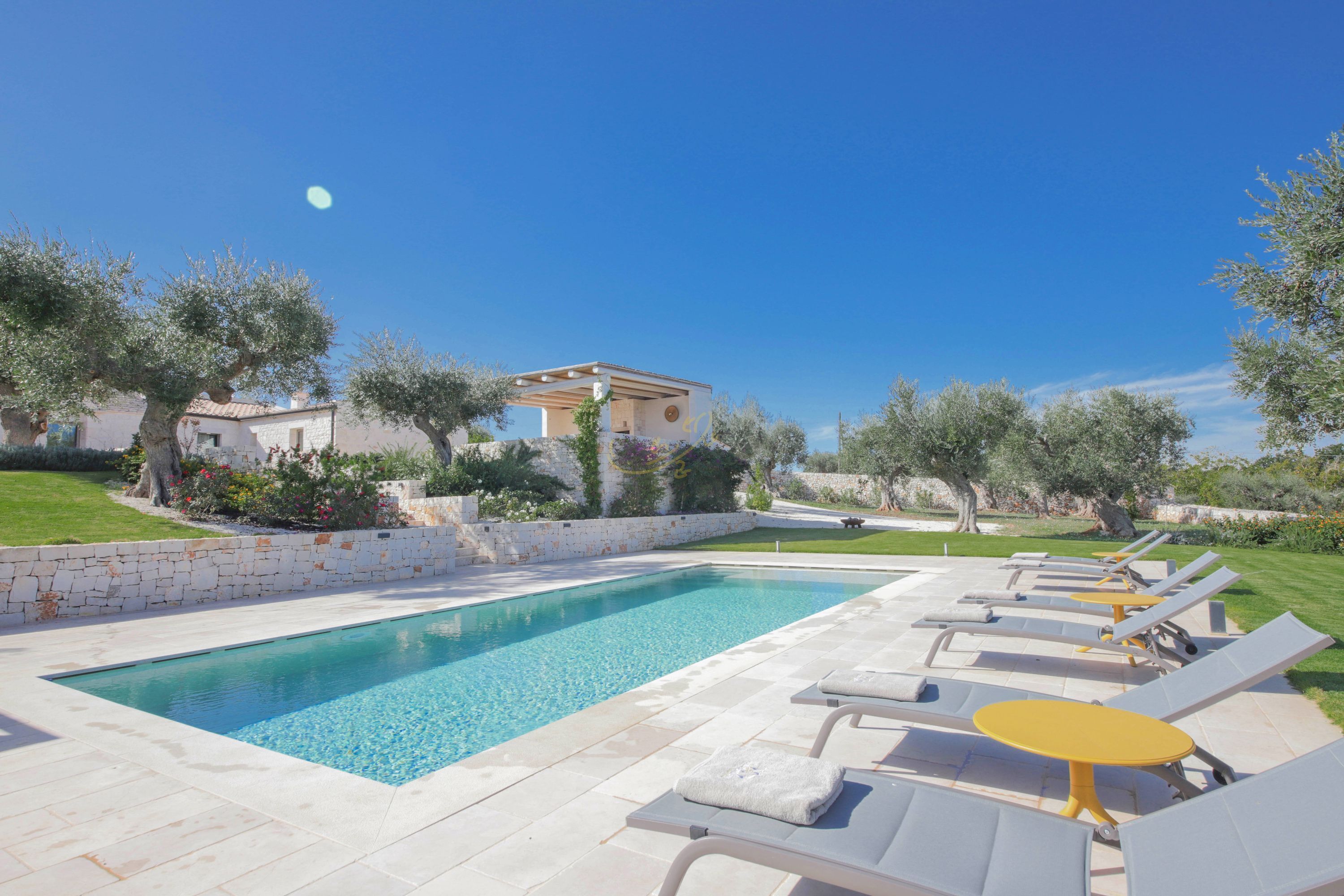 A swimming pool with lounge chairs and a small building in the background.