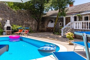 A swimming pool with lounge chairs and a barbecue grill. - Meja Stone House with Pool, Crikvenica, Croatia (Crikvenica)