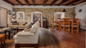 A living room with a sofa, coffee table, and dining area with chairs and a table. - Meja Stone House with Pool, Crikvenica, Croatia (Crikvenica)