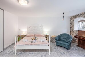 Quarto com cama, cadeira, mesa de cabeceira e parede de pedra.