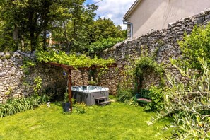 A backyard with a stone wall, a hot tub, and a pergola covered in greenery. - Meja Stone House with Pool, Crikvenica, Croatia (Crikvenica)