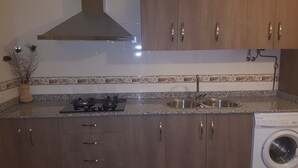 A kitchen with a gas stove, double sink, and a washing machine.