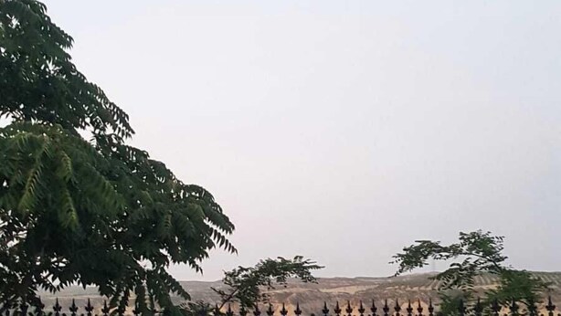 A table and four chairs with a view of a mountainous landscape.