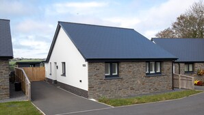 A modern house with a stone facade and a sloped roof. - The Paddock - Lovely Cottage With Hot Tub (Tenby)