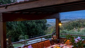 A covered outdoor dining area with a table set for two, overlooking a scenic landscape. - Villa Bel Panorama 8 Emma Villas (San Gimignano)