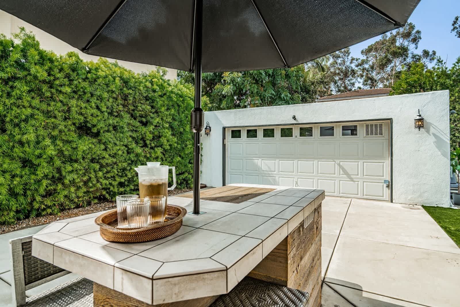A patio area with a table, a drink tray, and an umbrella.