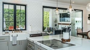 Una cocina moderna con una isla grande, azulejos blancos tipo metro y una ventana con marco negro.