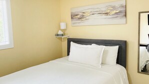 Ein Hotelzimmer mit Bett, Nachttisch, Lampe, einem Bild und einem Spiegel.