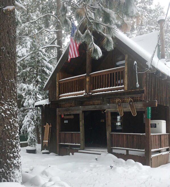 A wooden cabin with a porch, an American flag, and a sign indicating it is a campground.
