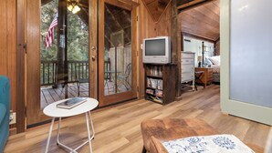Un interior de madera con una puerta corredera de vidrio, un televisor, una estantería y una mesita.
