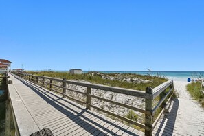 A wooden boardwalk leading to a beach with a clear sky.