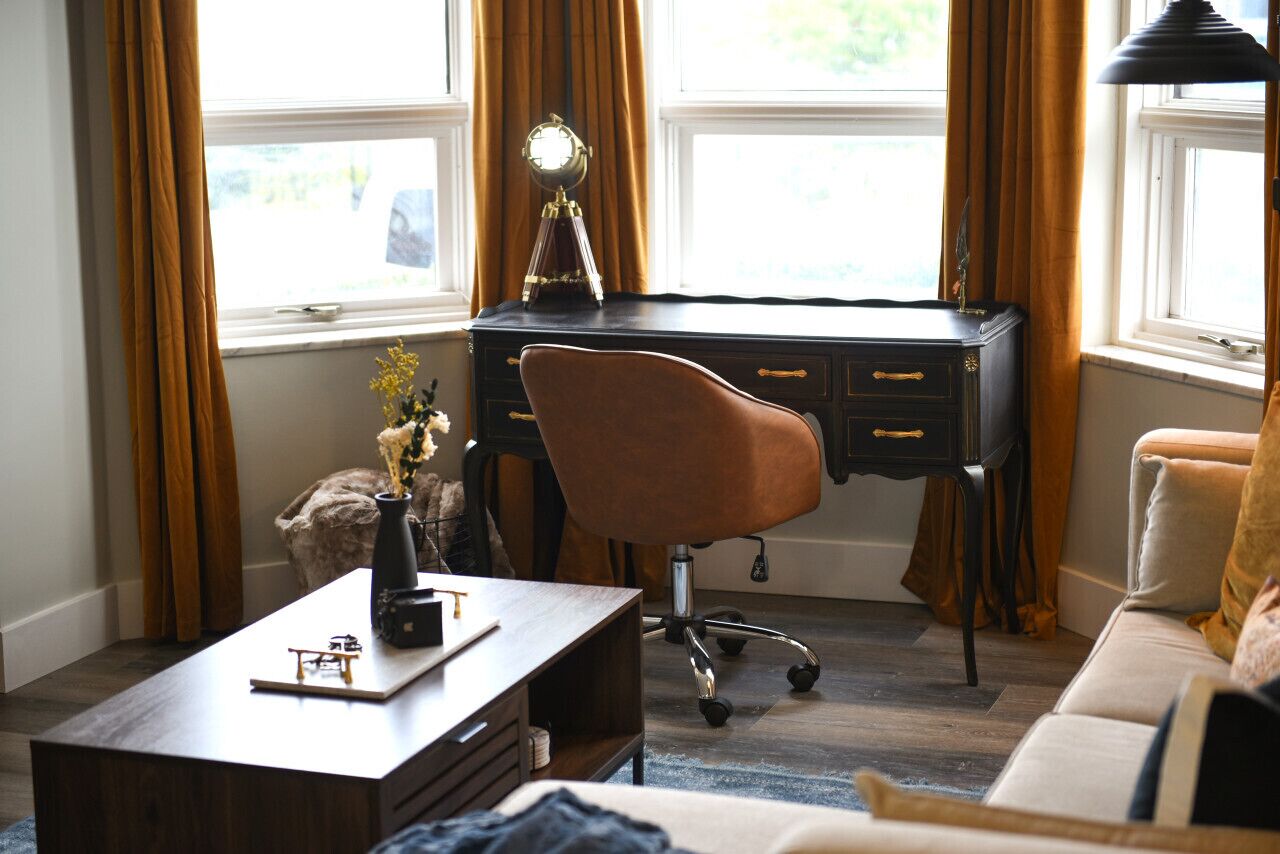 Une pièce comprenant un bureau, une chaise, un canapé et une lampe.