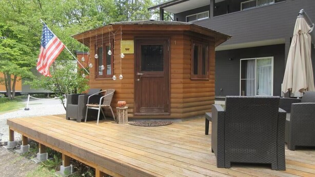 Una cabaña de madera con terraza, mobiliario exterior y una bandera estadounidense.