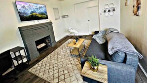 Ein Wohnzimmer mit Kamin, einer Couch, einem Couchtisch und einem an der Wand befestigten Fernseher.