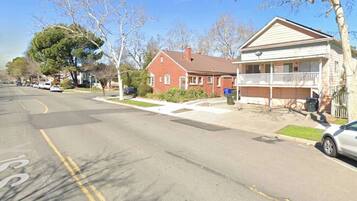 A residential street with houses, a clear sky, and a parked car.