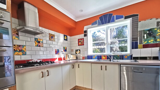 A kitchen with white cabinets, a stainless steel dishwasher, and a window with a view of greenery. - Make memories in this artists quarters.
Blue mosaic place - start to explore HB. (Waimarama)