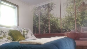 A bedroom with a large bed, a window with a view of trees, and a wooden bench. - Make memories in this artists quarters.
Blue mosaic place - start to explore HB. (Waimarama)
