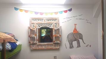 A child's bedroom with a bunk bed, a small table with a book, a decorative mirror, and a wall mural of an elephant and a fox.