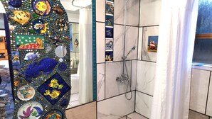 A bathroom with a shower, tiled walls, and a decorative mosaic wall. - Make memories in this artists quarters.
Blue mosaic place - start to explore HB. (Waimarama)