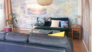 A cozy living room with a sofa, a coffee table, a lamp, and a wall with a beach mural. - Make memories in this artists quarters.
Blue mosaic place - start to explore HB. (Waimarama)